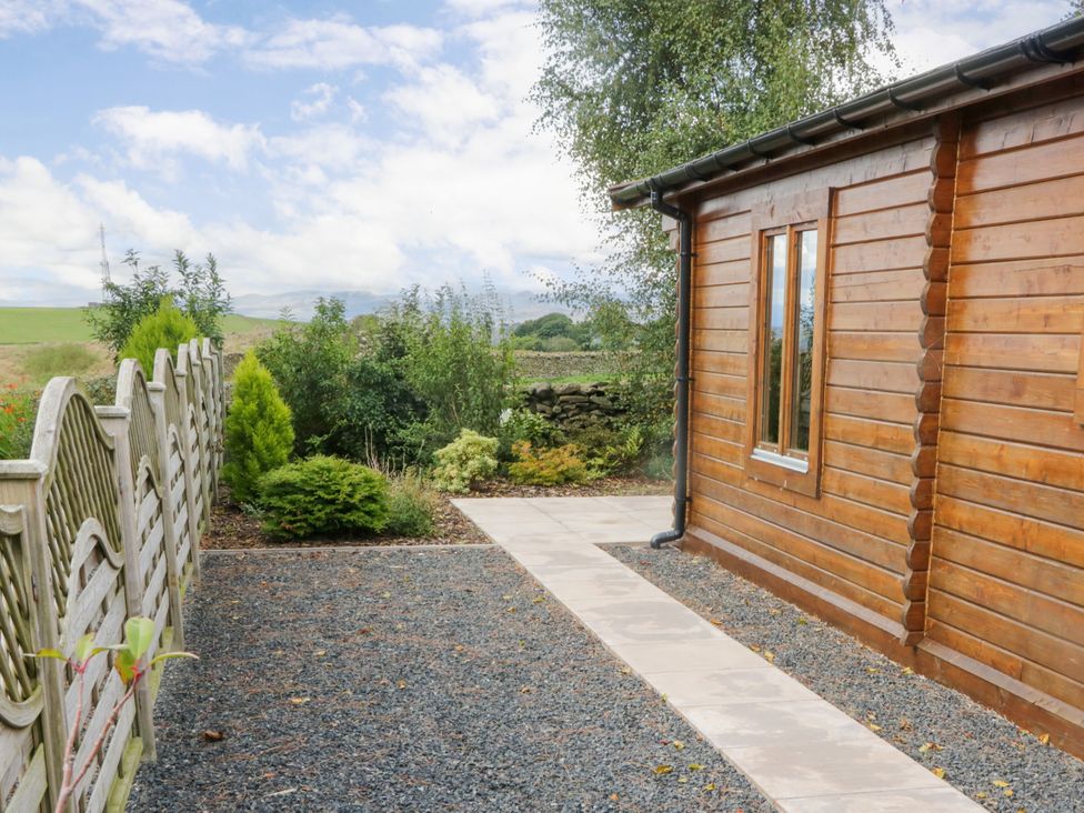 An outdoor view of a wooden cabin with a pathway and plants at Howgills Retreat Gatebeck near Kirkby Lonsdale