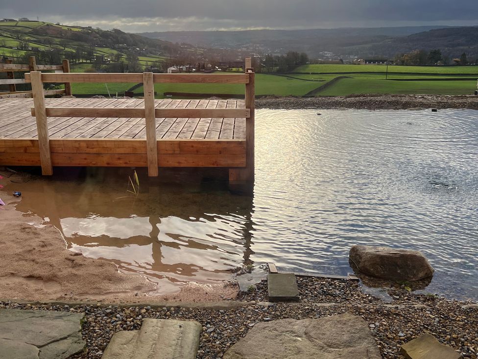 A deck over water with sand and stones at Spinners Cottage in East Morton