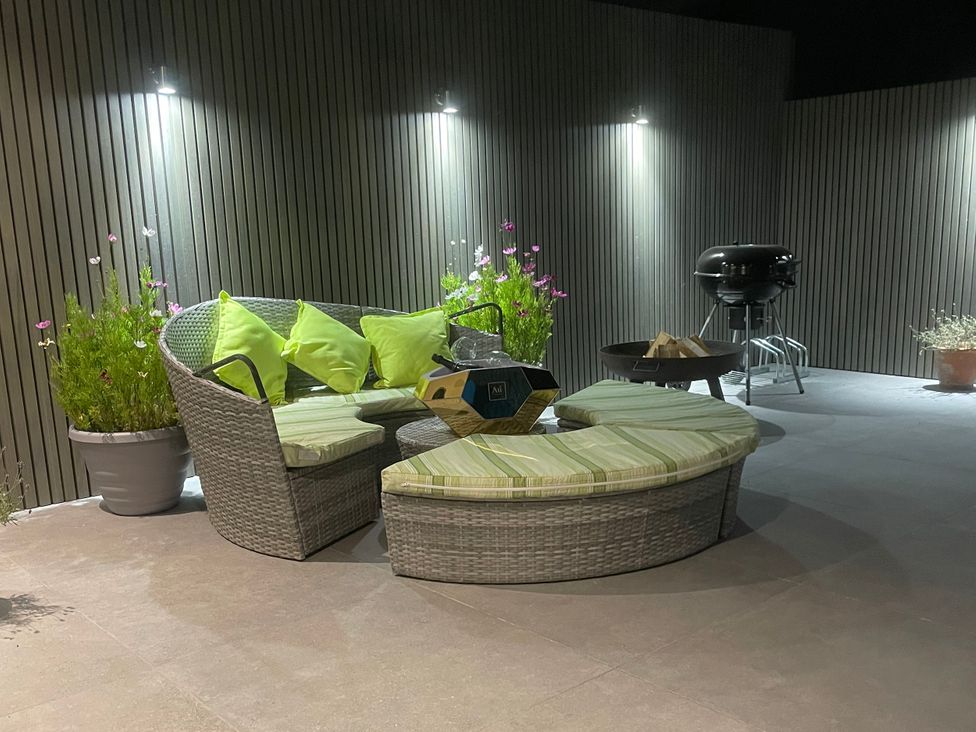 An outdoor seating area with cushions and a grill at Ninky Nonk in Bishop Sutton