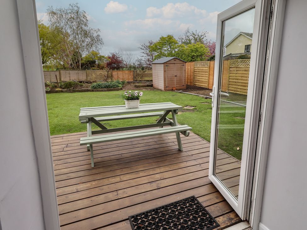 A patio area with a table and benches overlooking a garden at Country Retreat in Ponteland