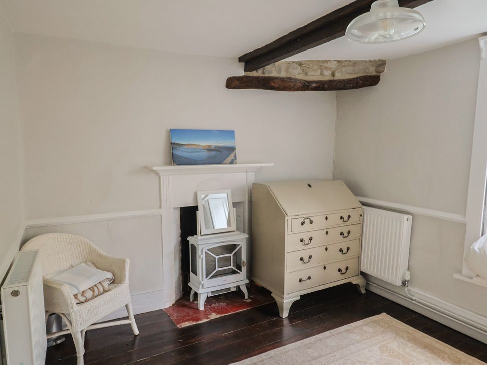 A bedroom with a fireplace and furniture at The Nest Lyme Regis