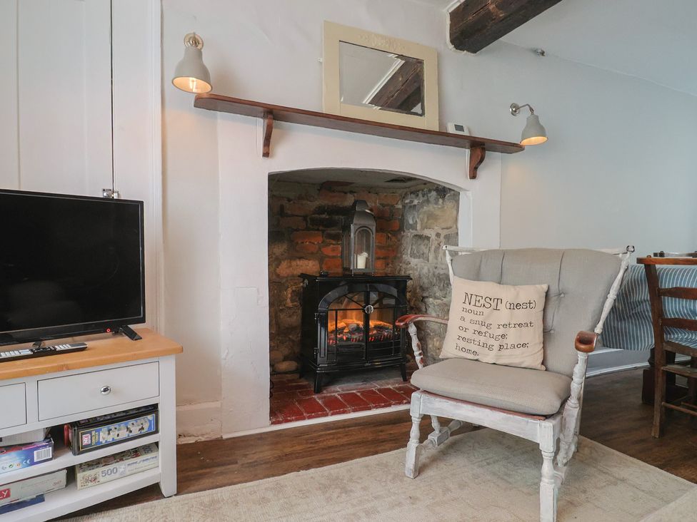 A living room with a television and a fireplace at The Nest in Lyme Regis