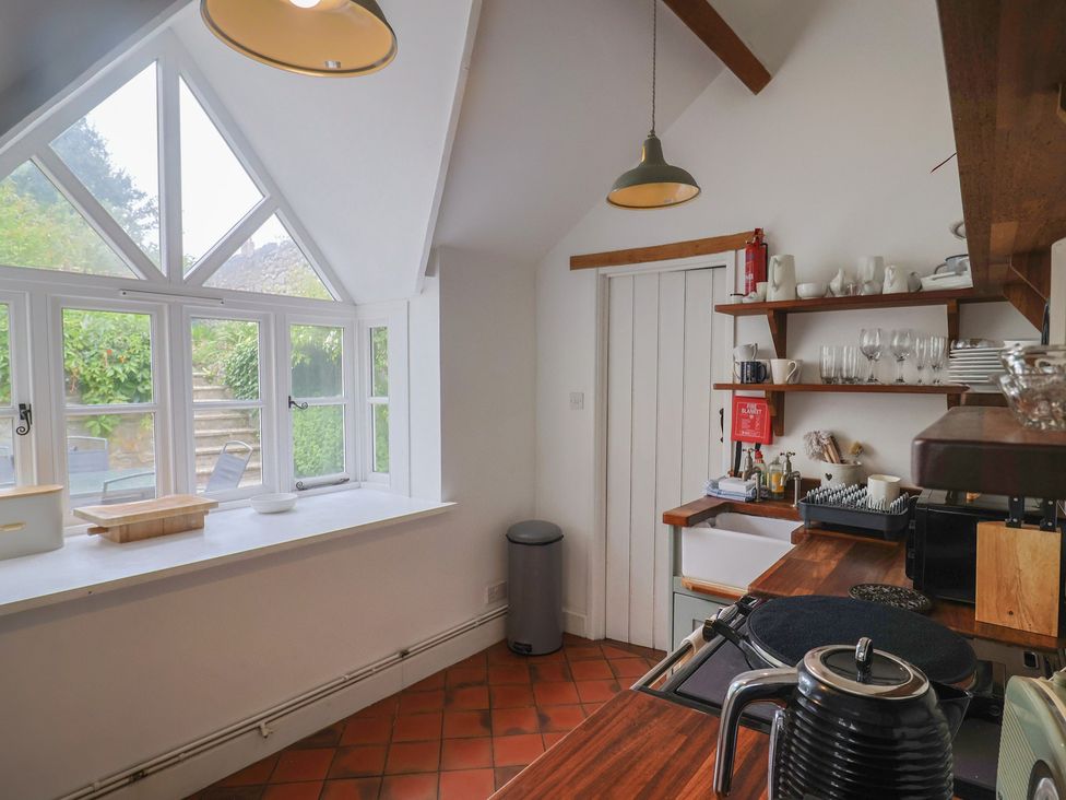 A kitchen with windows, counter, and shelves at The Nest Lyme Regis