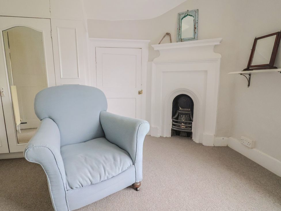 A sitting room with a chair and a fireplace at The Nest in Lyme Regis