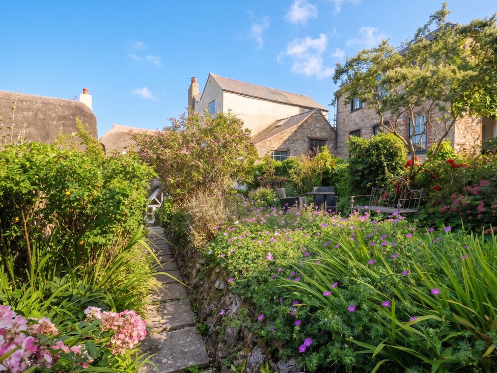 A garden with a pathway surrounded by flowers at The Nest in Lyme Regis
