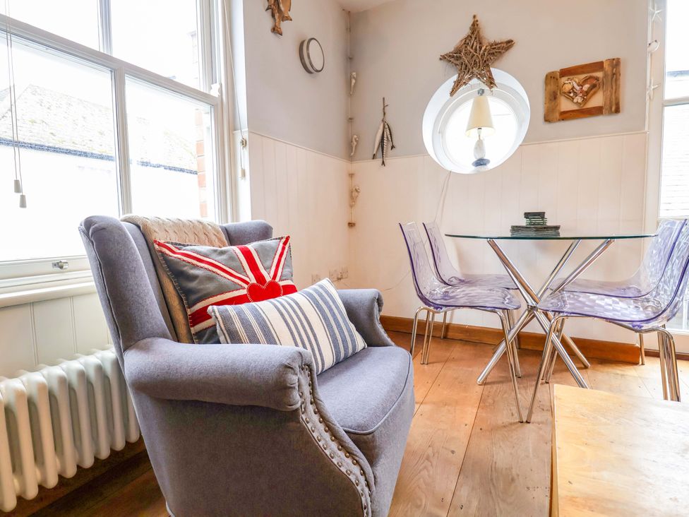 A dining room with an armchair and a glass table at Seaside in Lyme Regis