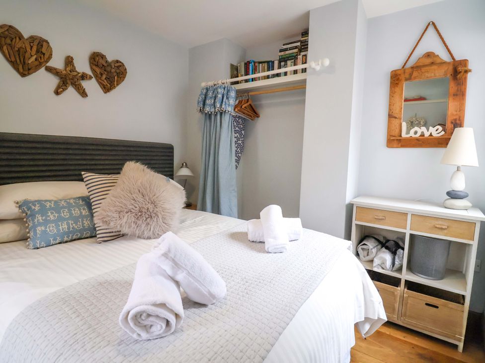 A bedroom with a bed and books on a shelf at Seaside in Lyme Regis