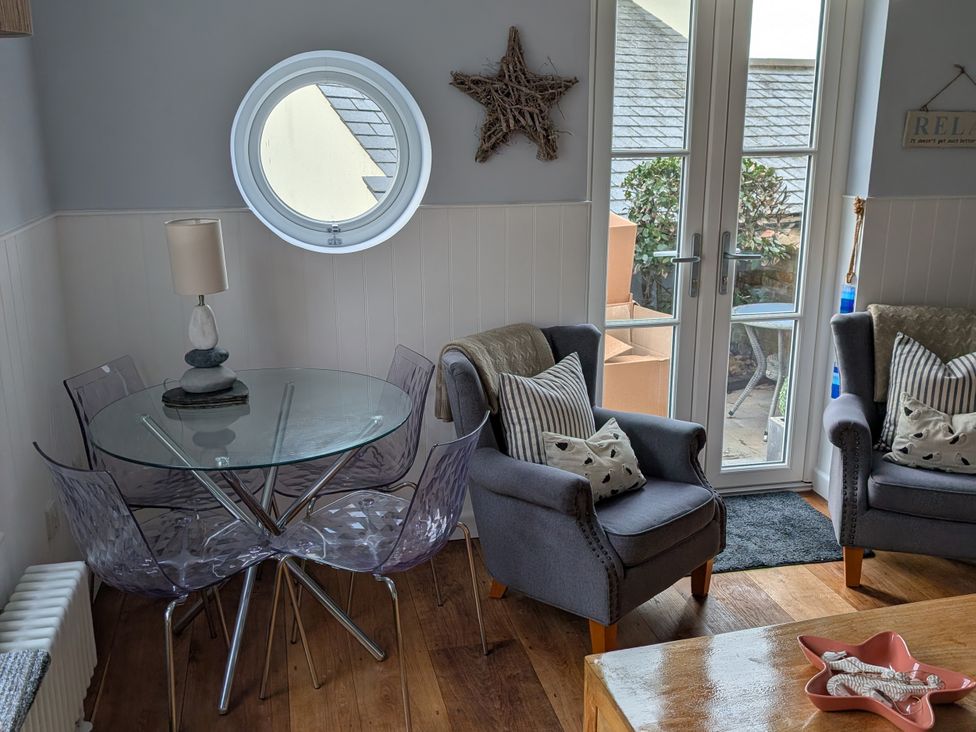 A living room with a round window and a glass table at Seaside in Lyme Regis