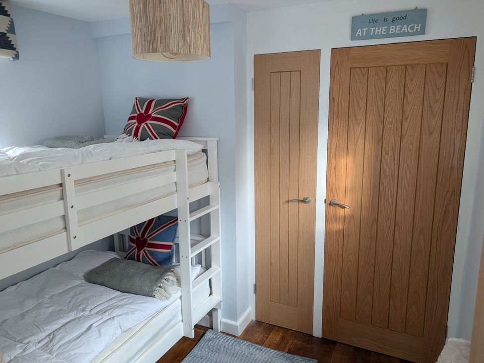 A bedroom with a bunk bed and doors at Seaside in Lyme Regis