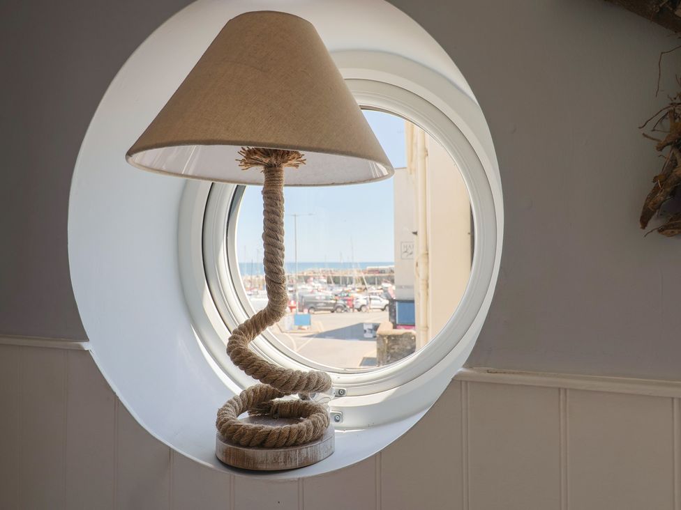A lamp by a circular window overlooking the harbor at Seaside in Lyme Regis