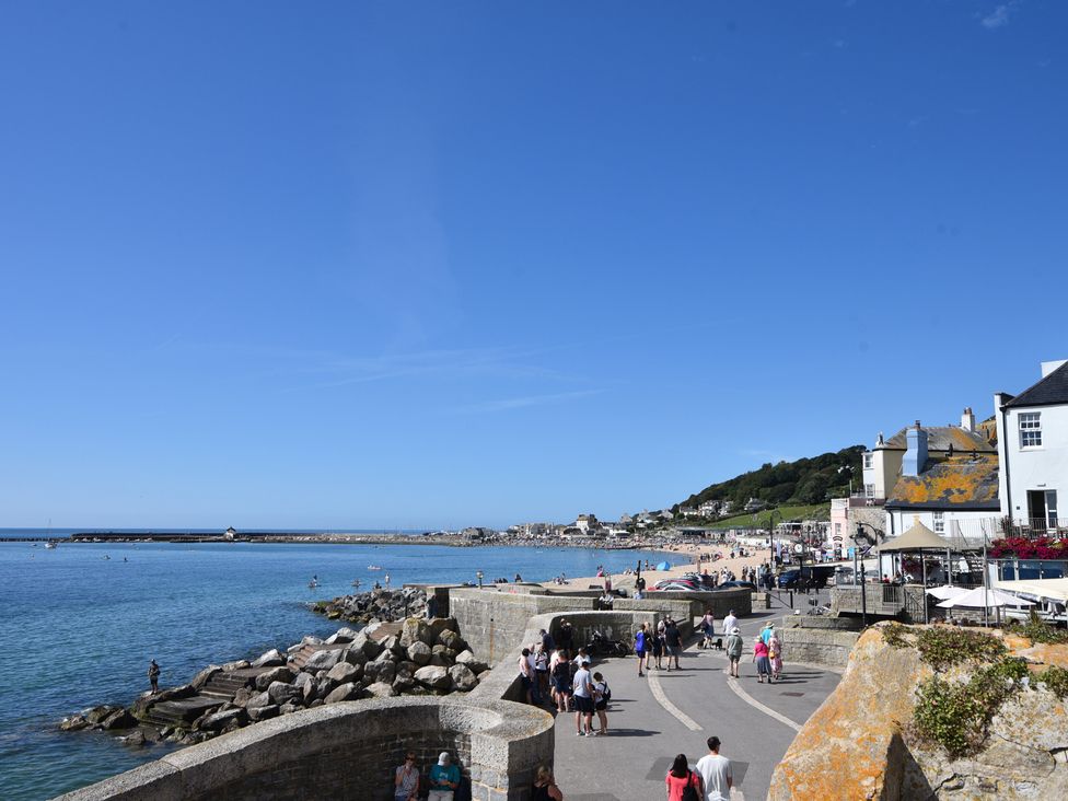 A seaside view with a beach and people walking at Greystones Flat in Lyme Regis