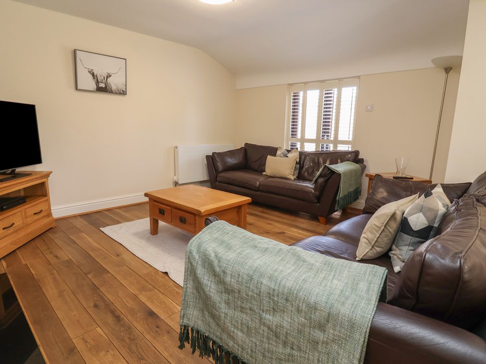 A living room with a television and leather sofas at 4 Green Farm Cottage Saughall