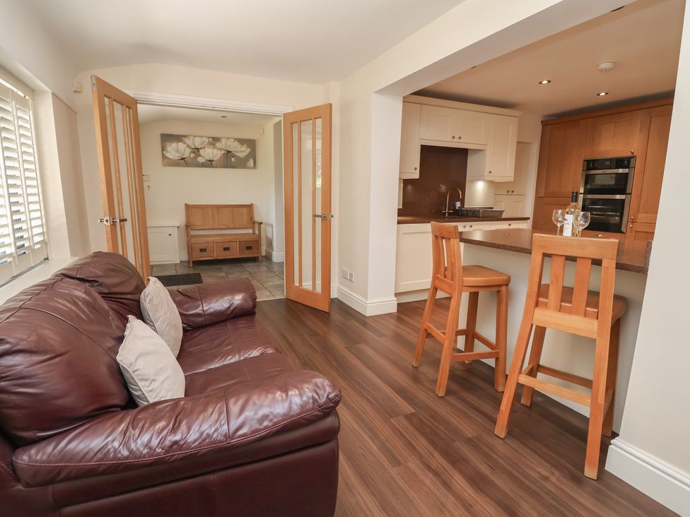 A living room with a sofa and bar stools at 4 Green Farm Cottage Saughall