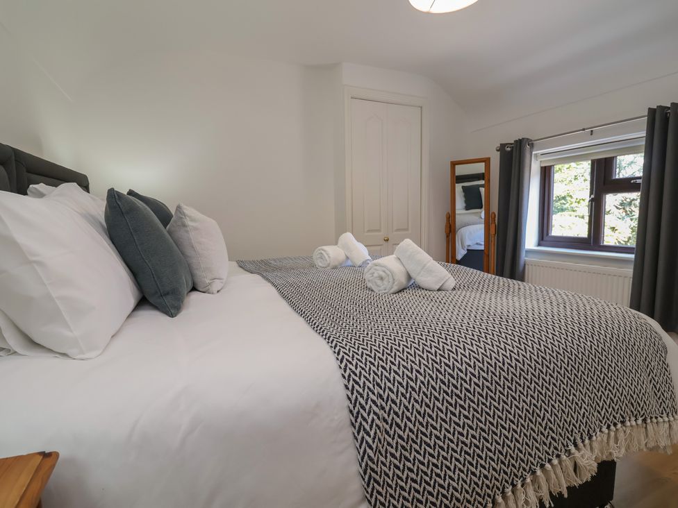 A bedroom with a large bed and window at 4 Green Farm Cottage Saughall