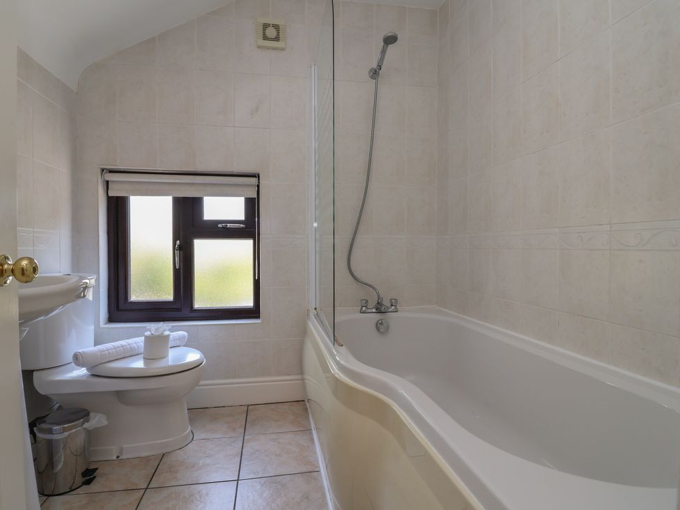A bathroom with a bathtub and toilet at 4 Green Farm Cottage Saughall