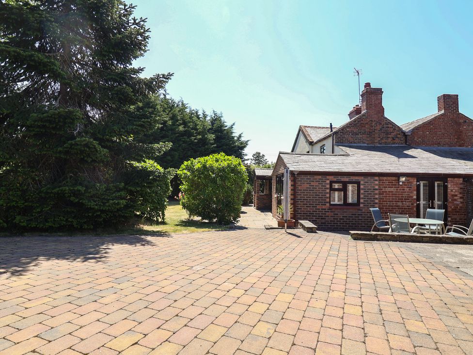 An outdoor area with a house and patio furniture at 4 Green Farm Cottage in Saughall
