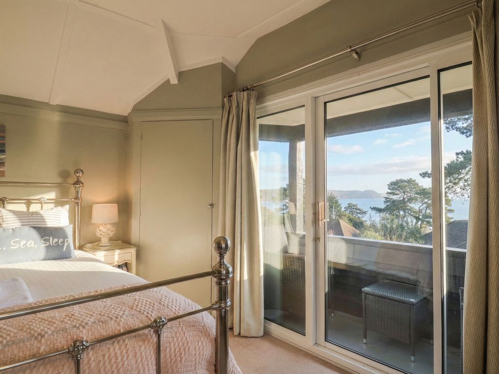 A bedroom with a bed and sliding door leading to a deck at Maries, Lyme Regis