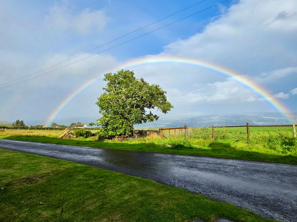 A landscape with a rainbow over a tree beside a road at Ceol-na-Mara Newport near Dunbeath