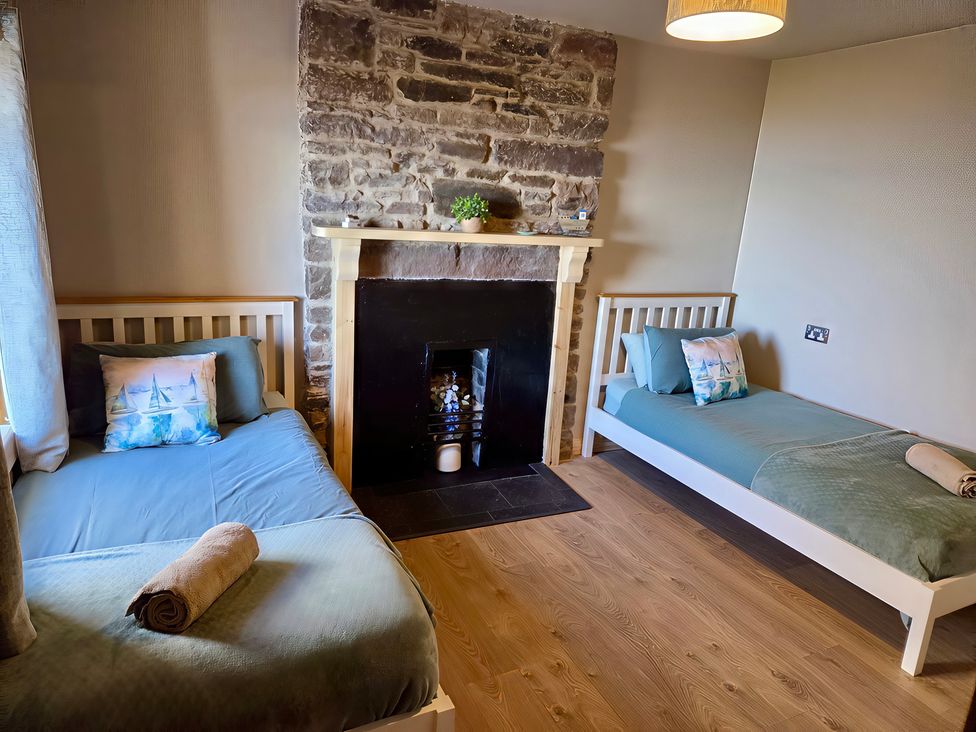 A bedroom with two beds and a fireplace at Ceol na Mara Newport near Dunbeath