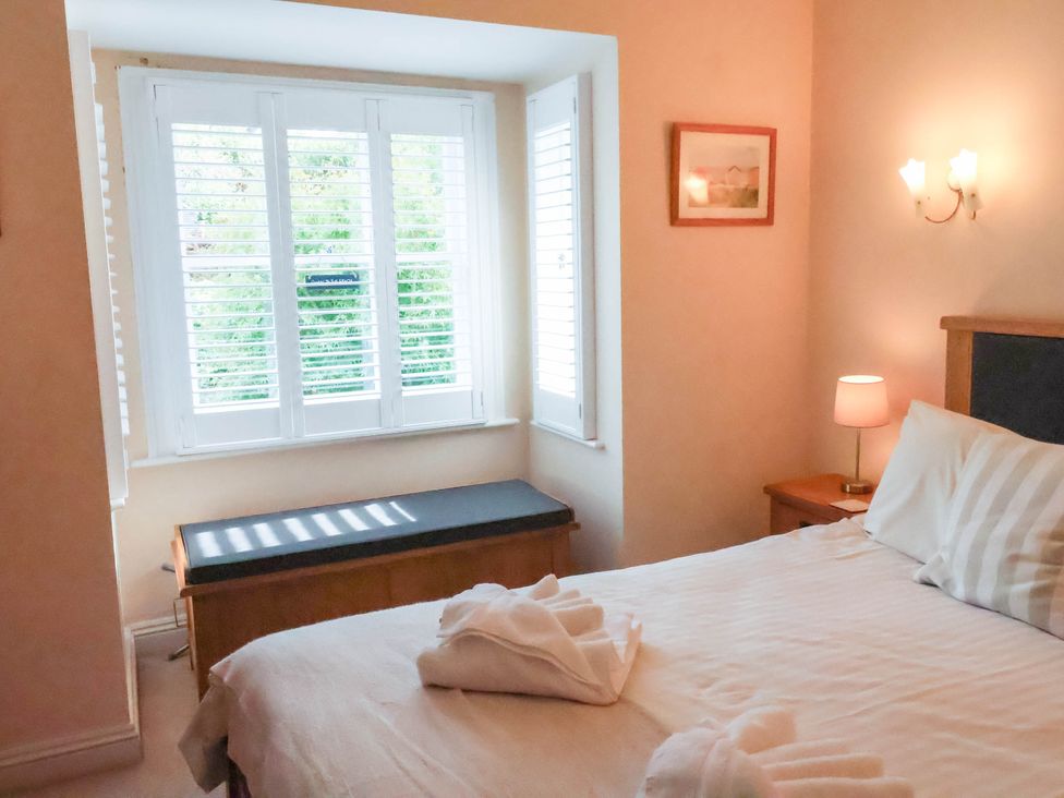 A bedroom with a bed and window at The Bolthole in Lyme Regis