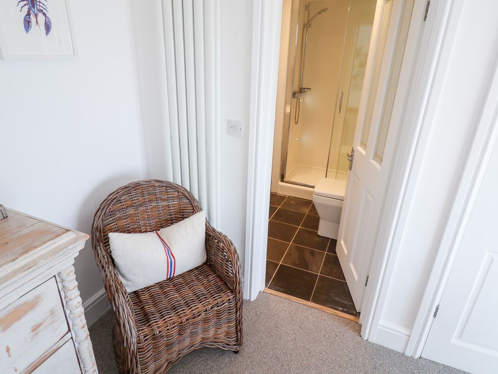 A bathroom with a shower and toilet seen from an adjacent room at Seagull in Lyme Regis