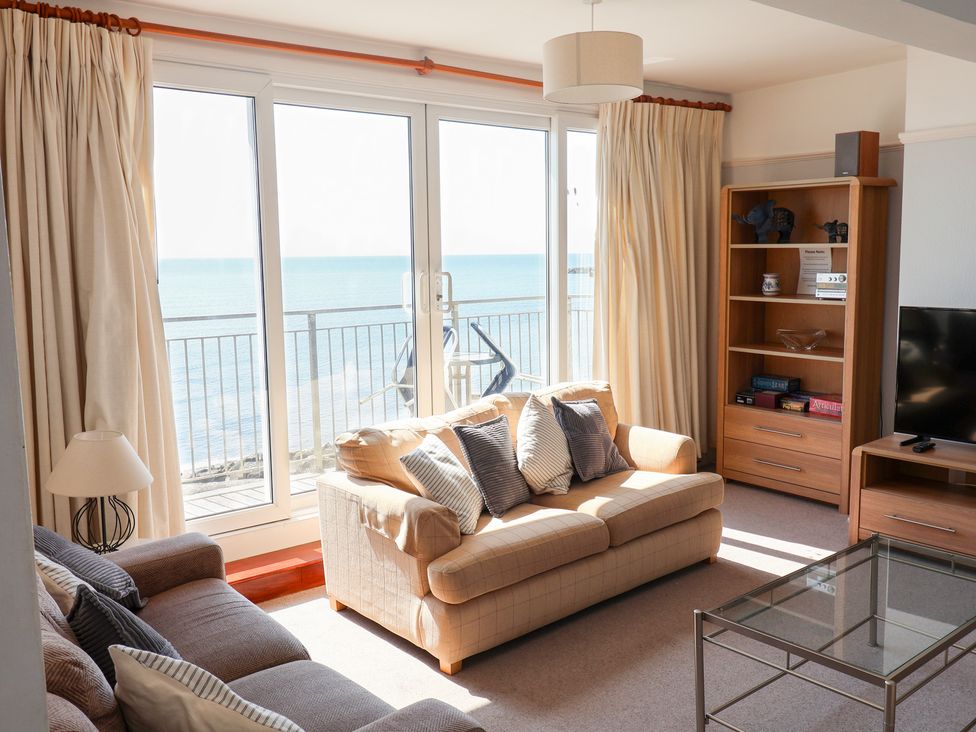 A living room with a view of the sea and furniture at Watersmeet in Lyme Regis