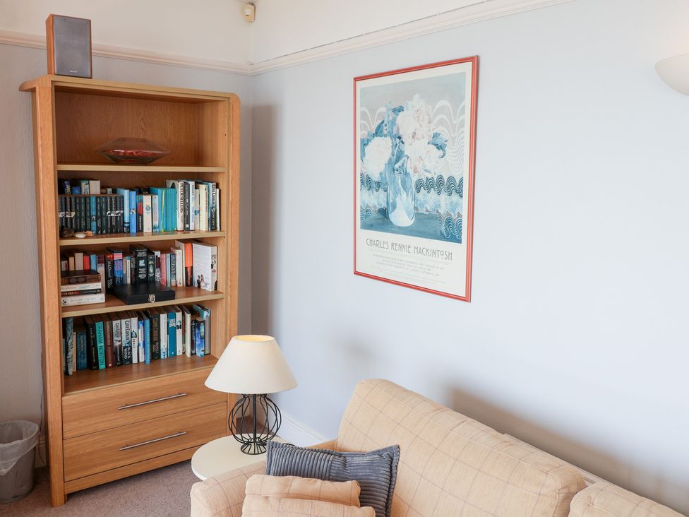 A living room with a bookshelf and a lamp at Watersmeet in Lyme Regis