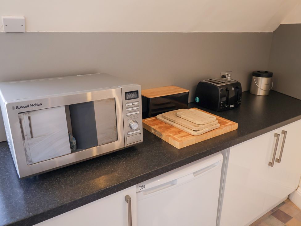 A kitchen counter with a microwave toaster and chopping board at Watersmeet Lyme Regis