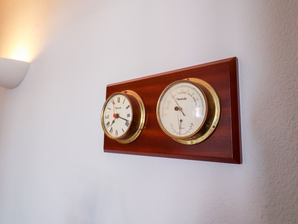 A clock and barometer mounted on a wooden panel at Watersmeet in Lyme Regis