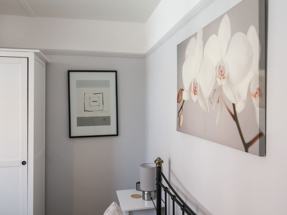 A bedroom with a bed, lamp, and artwork at Watersmeet Lyme Regis