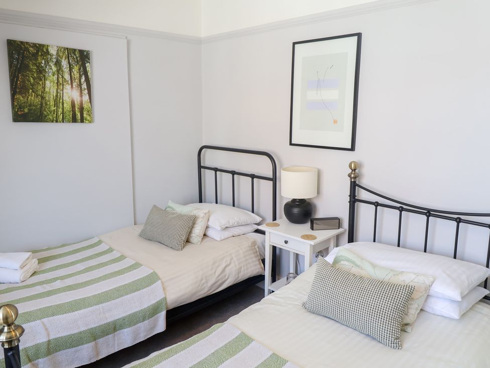A bedroom with two beds and a bedside table at Watersmeet in Lyme Regis