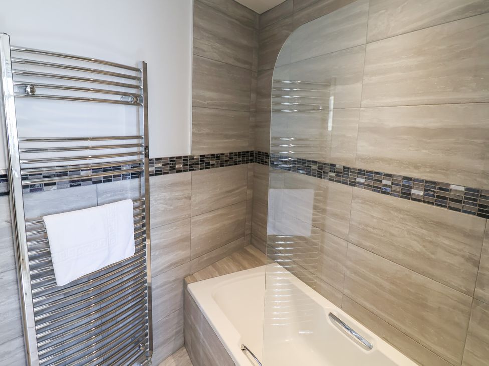 A bathroom with a bathtub and towel rail at Watersmeet in Lyme Regis