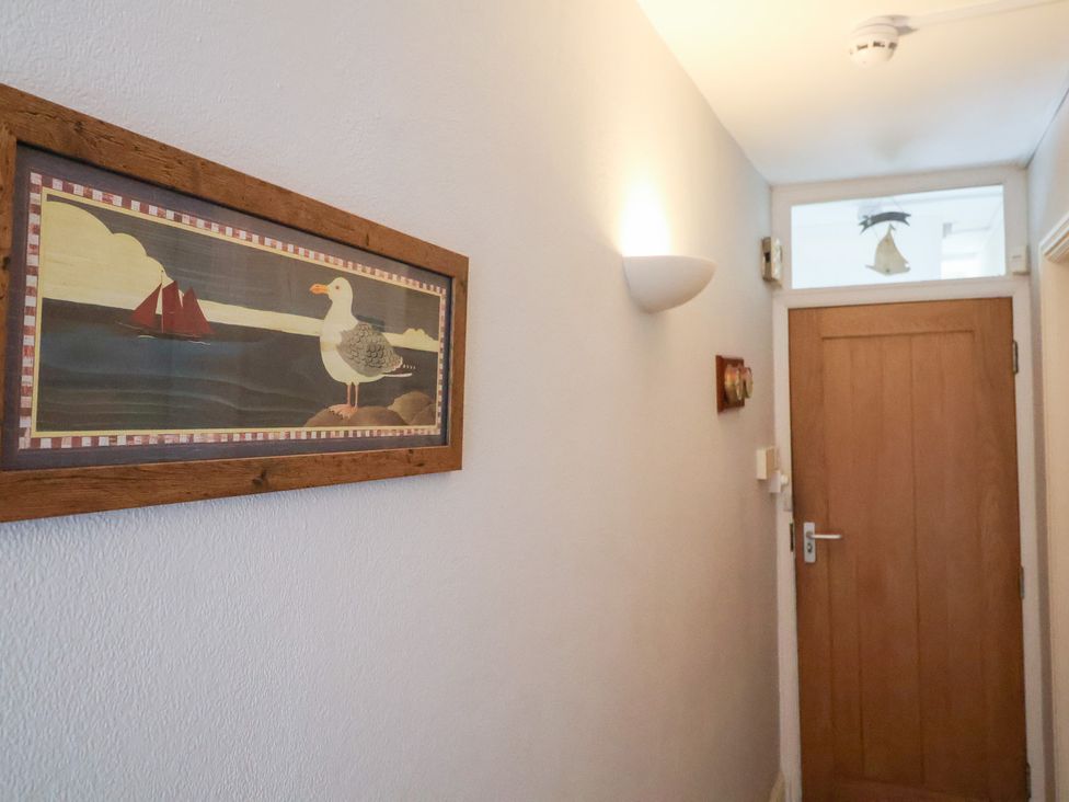 A hallway with a seagull painting and a wooden door at Watersmeet in Lyme Regis