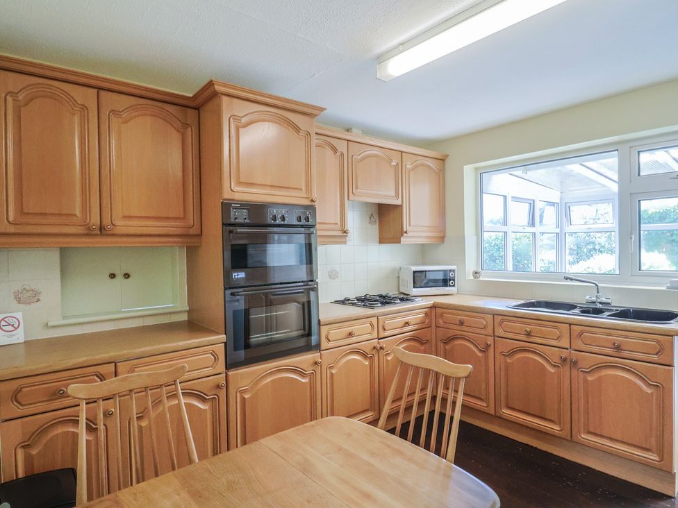 A kitchen with wooden cabinets and appliances at Gosling Way Lyme Regis