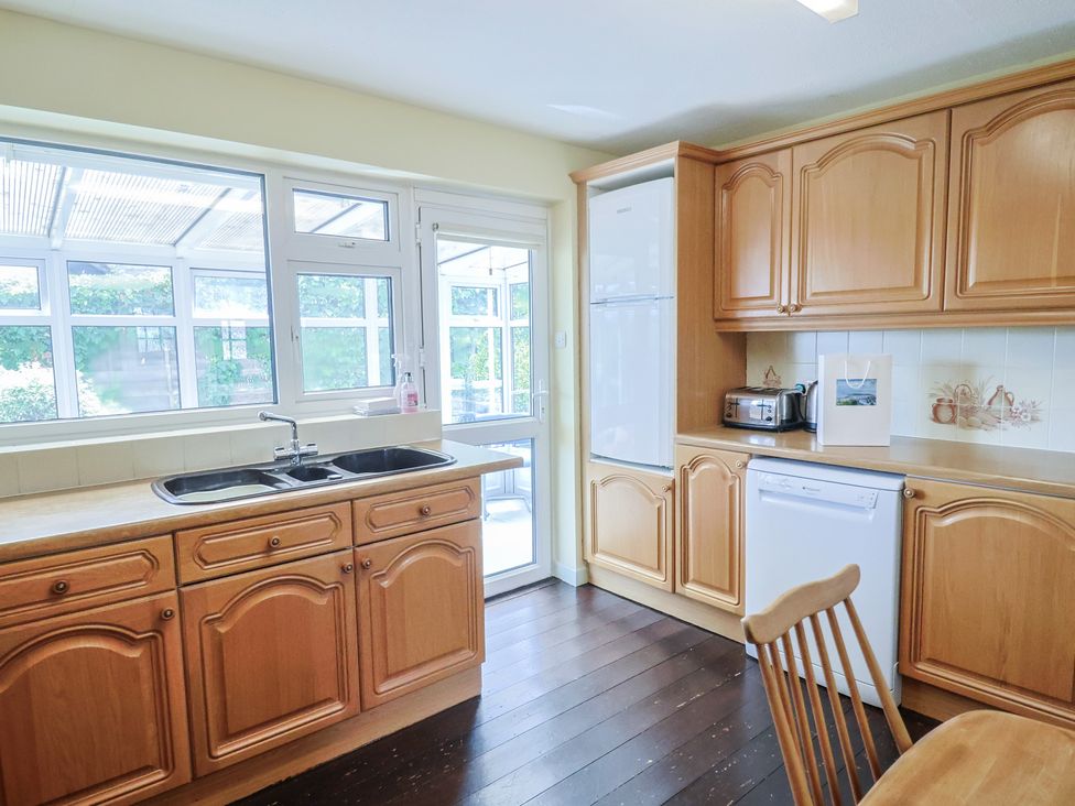 A kitchen with wooden cabinets and appliances at Gosling Way Lyme Regis