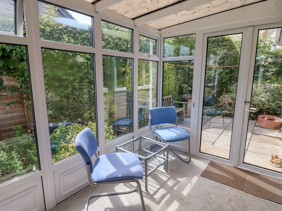 A conservatory with a glass table and chairs at Gosling Way in Lyme Regis