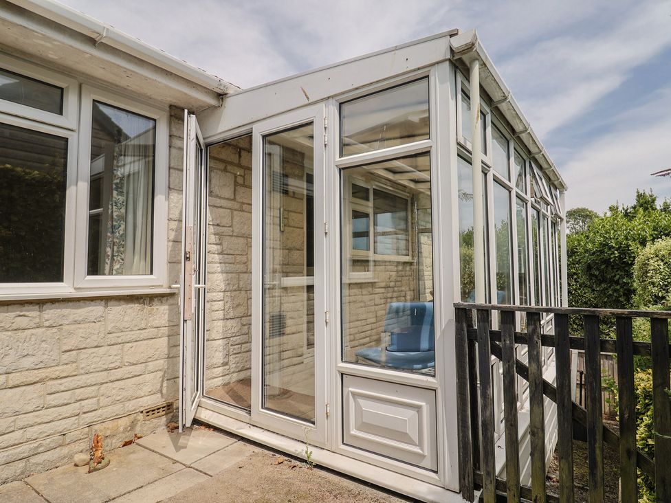 A conservatory with glass panels and a chair at Gosling Way in Lyme Regis