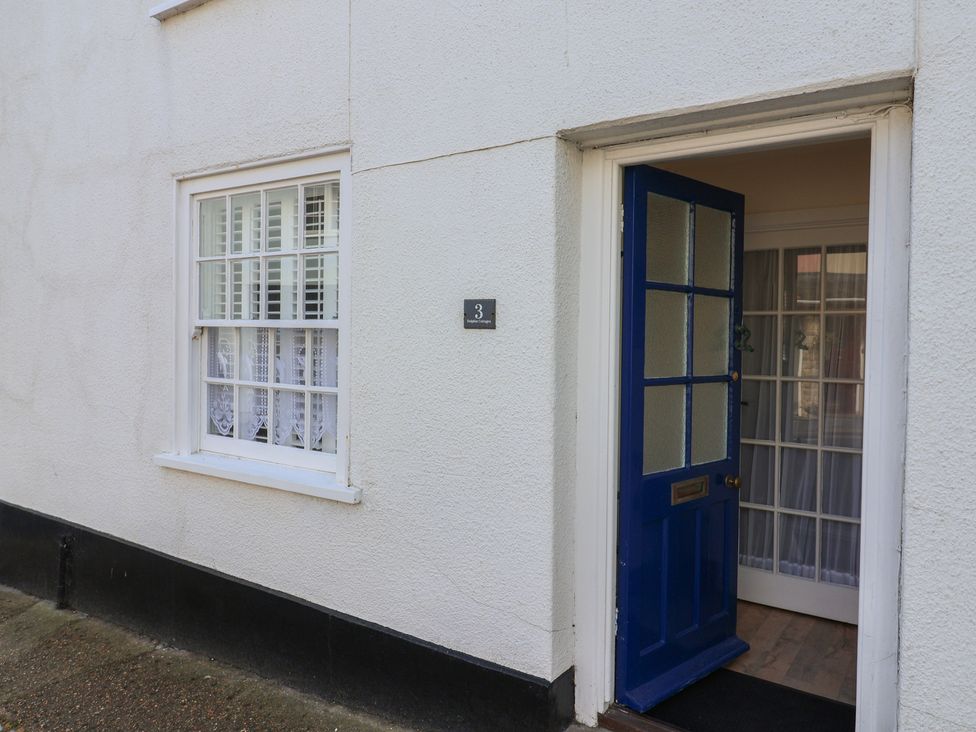An entrance with a blue front door and window at 3 Dolphin Cottages in Lyme Regis