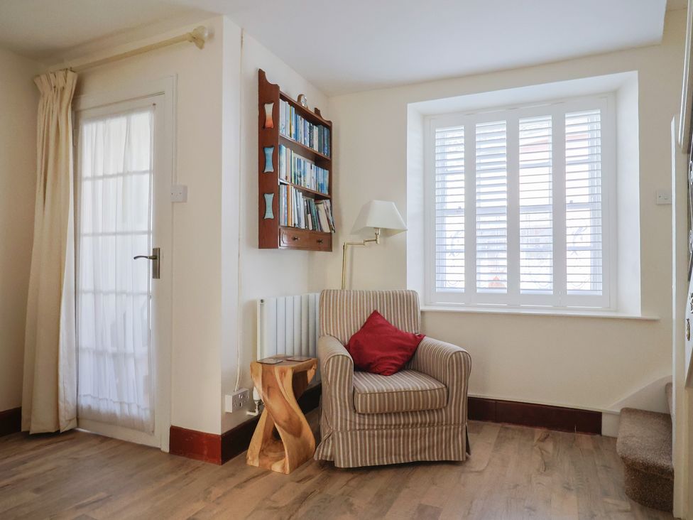 A living room with a chair and bookshelf at 3 Dolphin Cottages in Lyme Regis