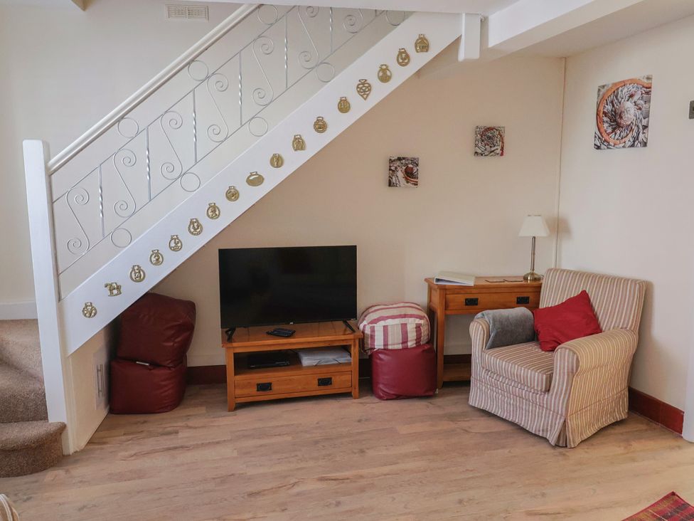 A living room with a television and armchair at 3 Dolphin Cottages in Lyme Regis
