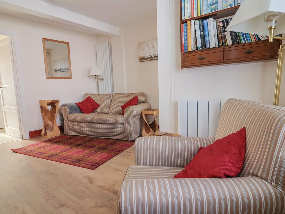 A living room with a sofa and bookshelf at 3 Dolphin Cottages in Lyme Regis
