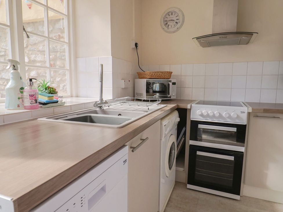 A kitchen with a sink, dishwasher, oven, and microwave at 3 Dolphin Cottages in Lyme Regis