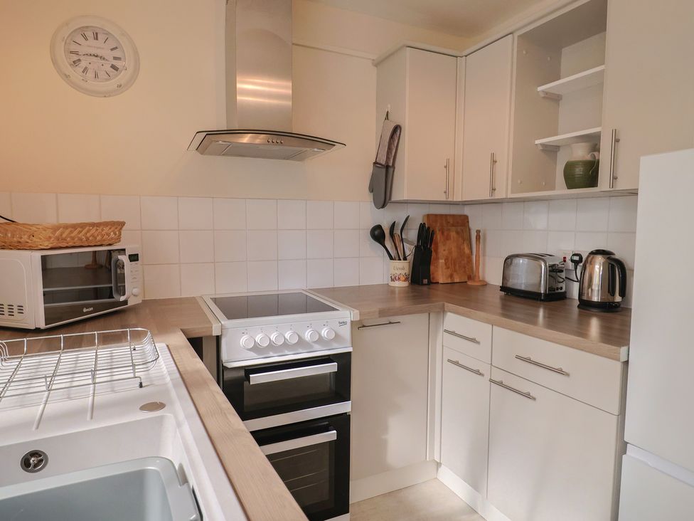 A kitchen with a stove, microwave and cabinets at 3 Dolphin Cottages in Lyme Regis