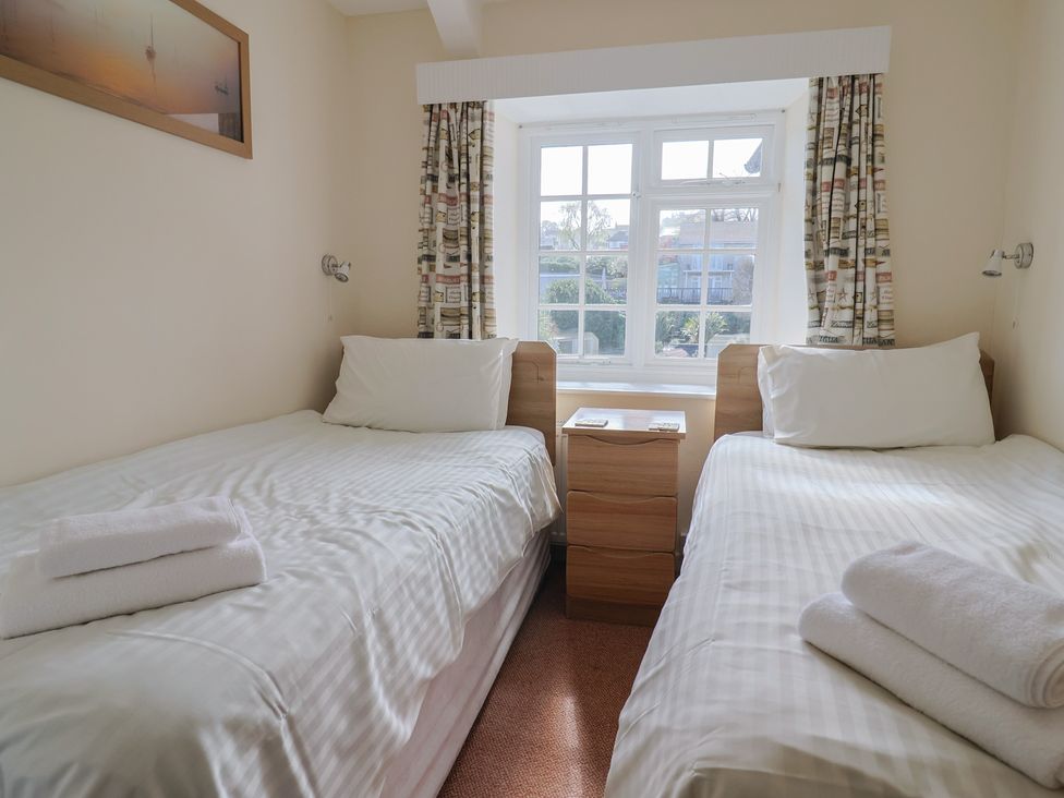 A bedroom with two single beds and a window at 3 Dolphin Cottages Lyme Regis