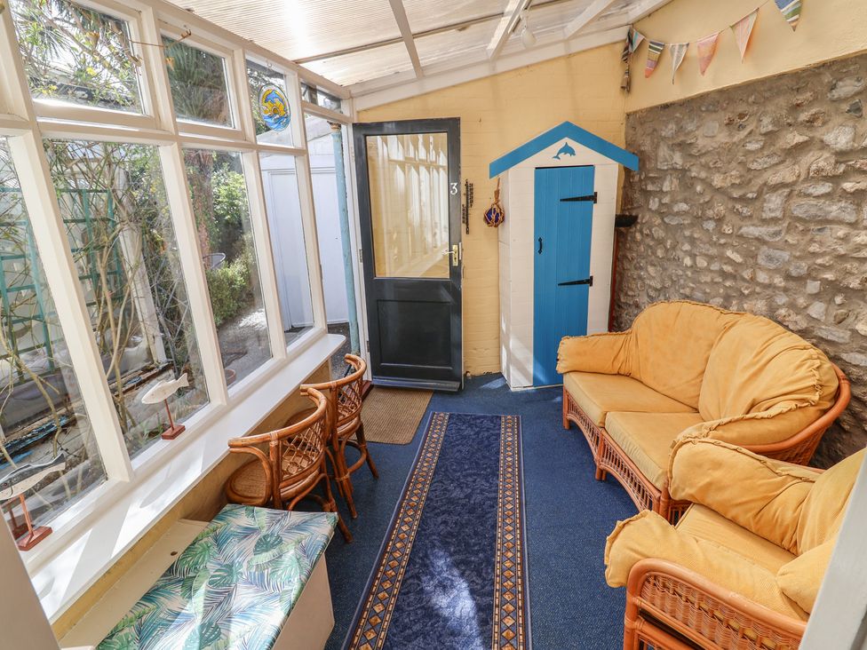 A conservatory with seating and a door at 3 Dolphin Cottages in Lyme Regis