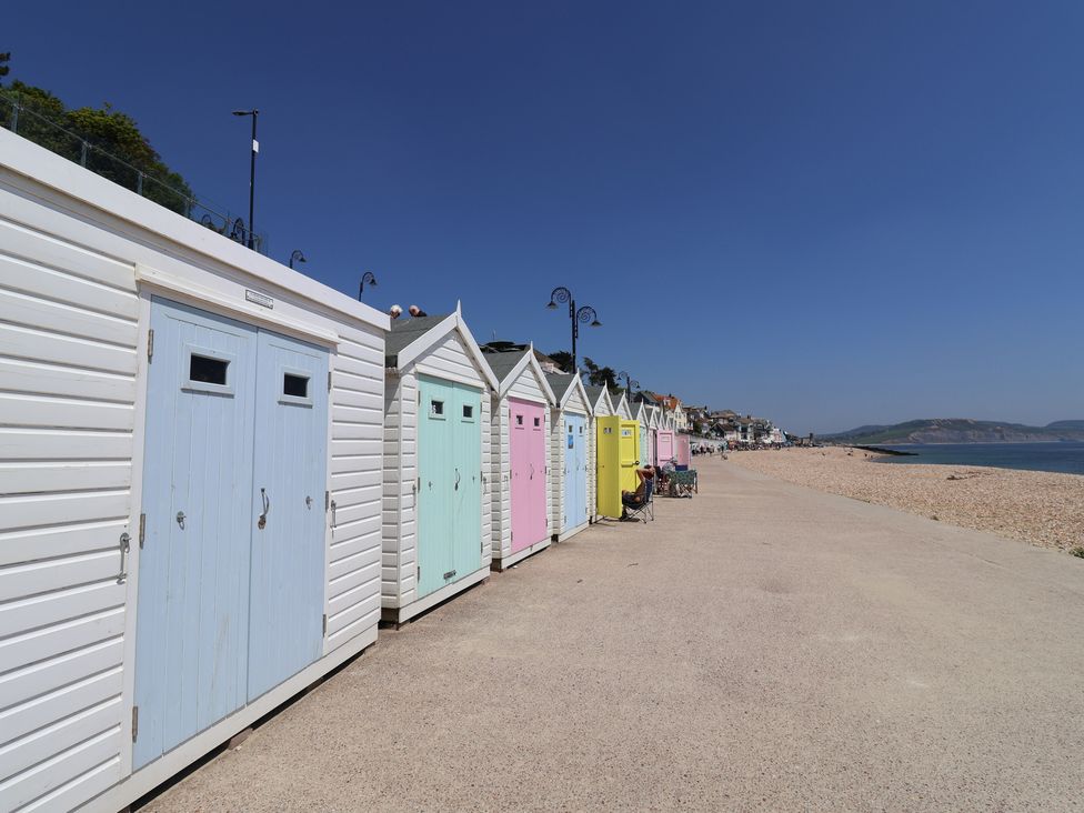 A row of beach huts along a pathway at 3 Dolphin Cottages Lyme Regis