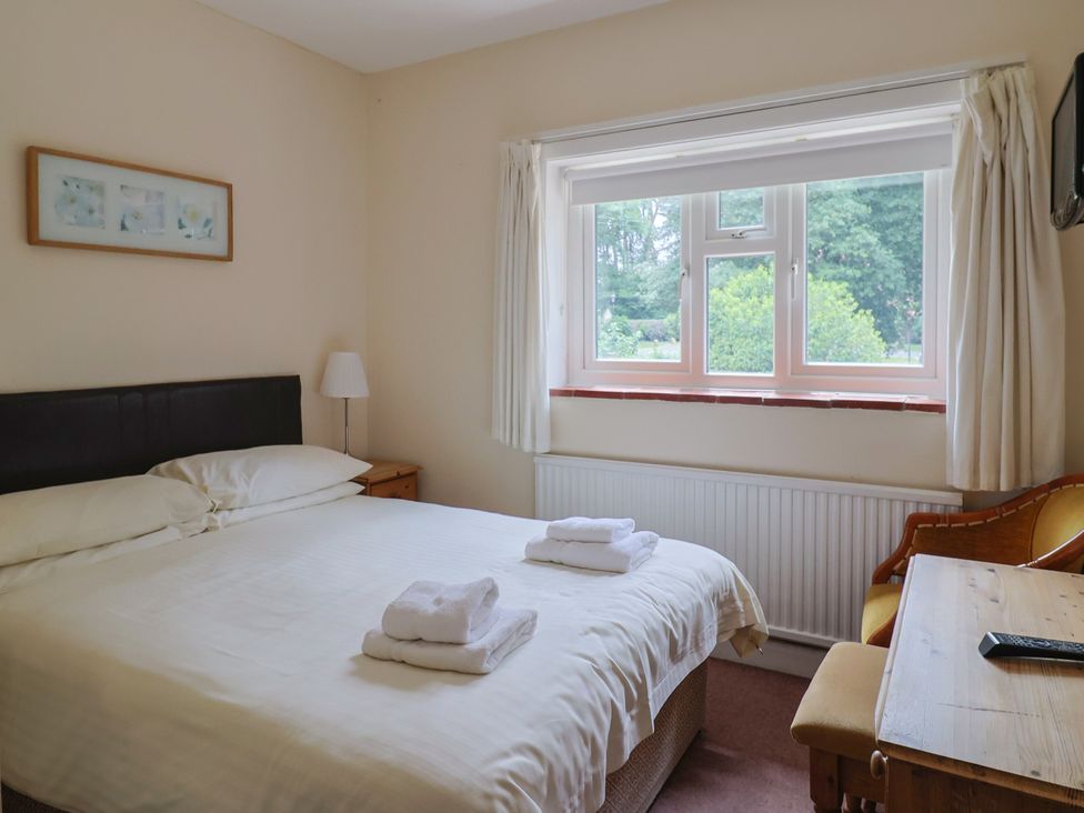 A bedroom with a bed and desk at The Orchard Country House in Rousdon