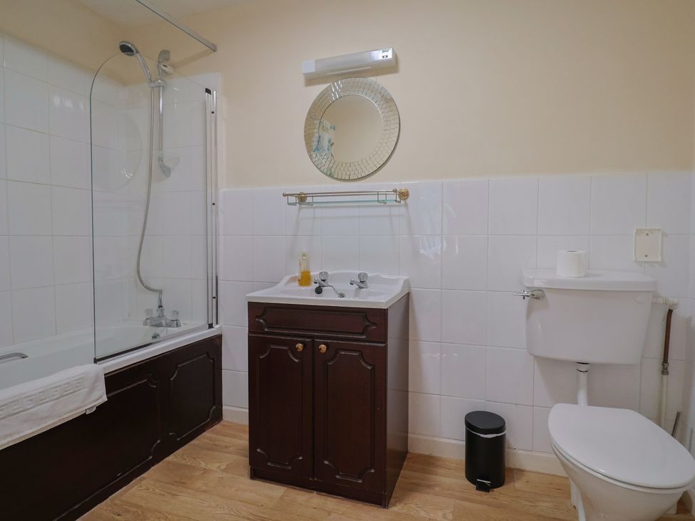 A bathroom with a bathtub, sink, toilet, and mirror at The Orchard Country House Rousdon