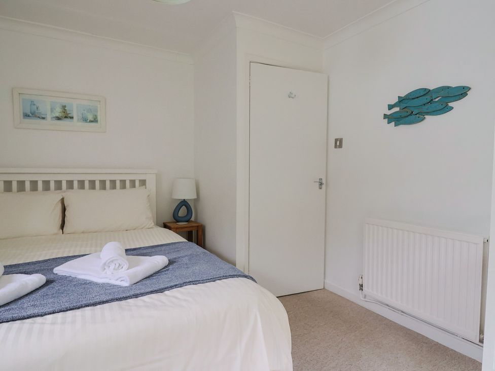 A bedroom with a bed, lamp and wall decor at High Trees in Lyme Regis