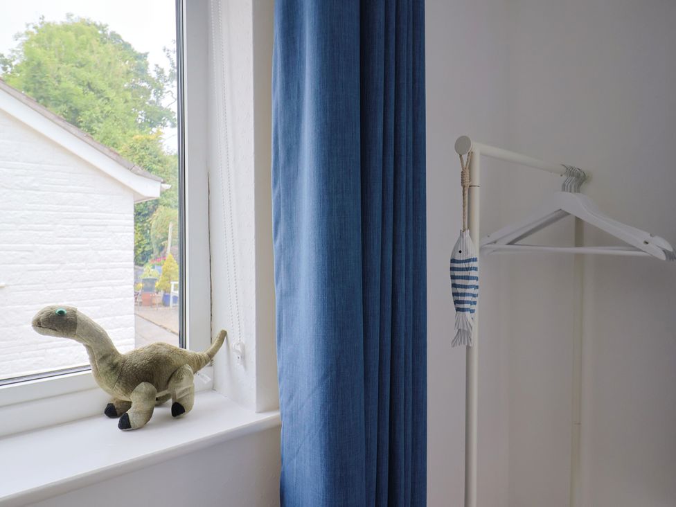 A bedroom window with a toy dinosaur and a clothes hanger at High Trees in Lyme Regis